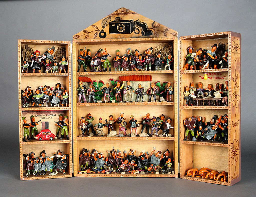 An image of a retablo. The retablo has a likeness to an open cabinet with shelves, each containing figurines portraying different scenes.