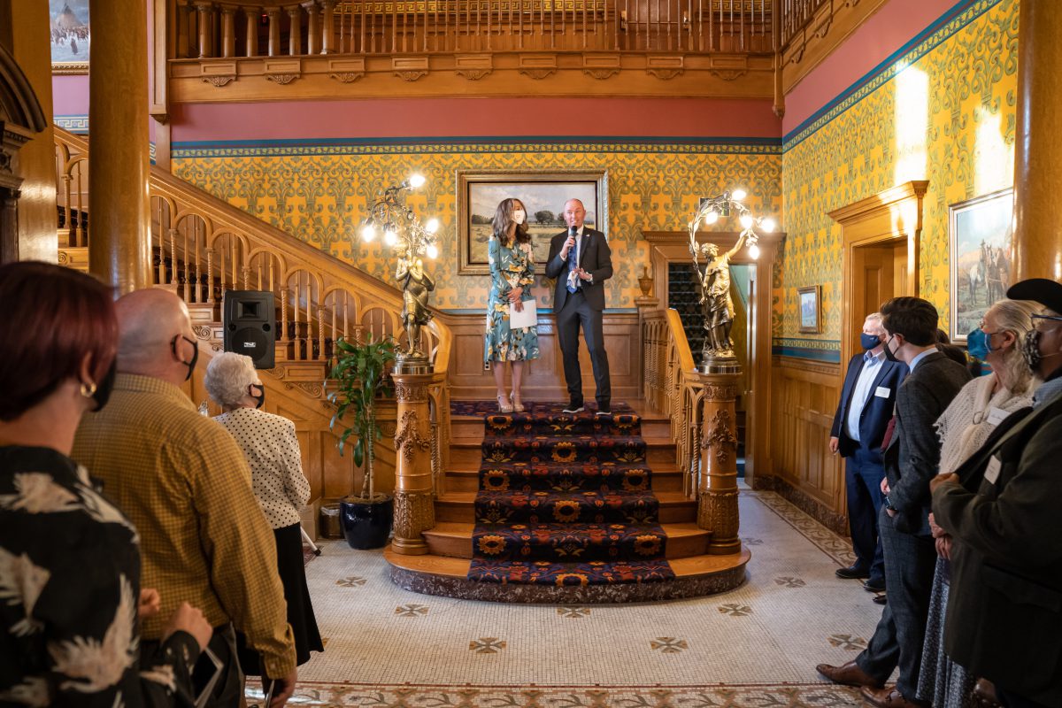 Governor and Mrs. Cox stand on a set of stairs talking to a group standing with face masks on.