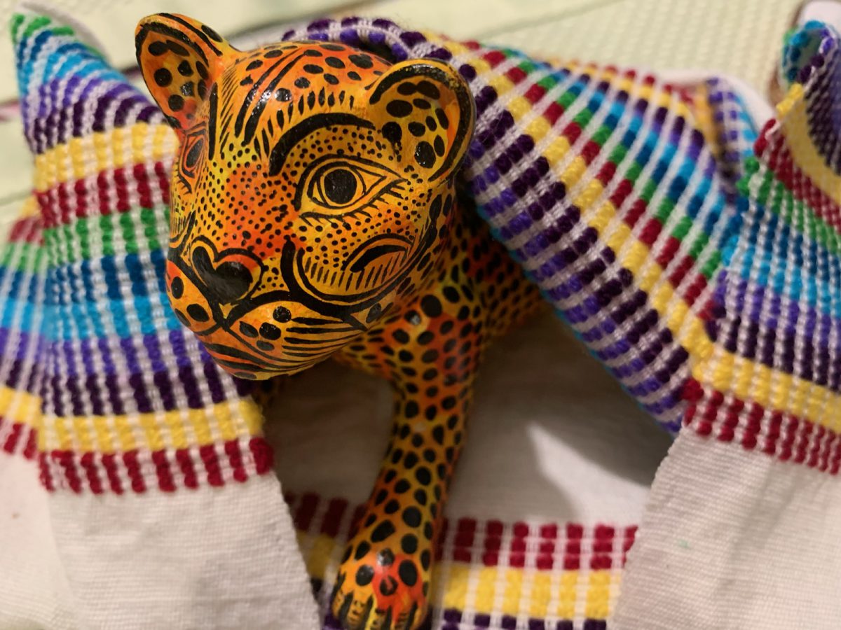 A colorful tiger sculpture rests in a woven textile.