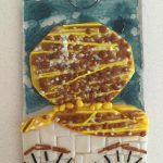 Textured glass art and tiles resembling a hair bun and pair of eyes.