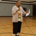 Teaching artist Eleanor Tom speaking at a microphone