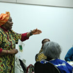 Teaching artist Joan Effiong speaking to a group of adults ina classroom