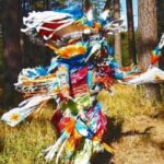 A colorful, motion-blurred image of Patrick Willie dancing in full regalia