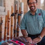 Teachig Artist Roger Clark posing with a collection of wooden flutes