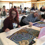 Workshop participants creating chalk drawings at a table