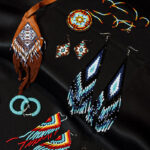 A diverse array of handmade beaded jewelry laid out on a smooth black fabric surface.