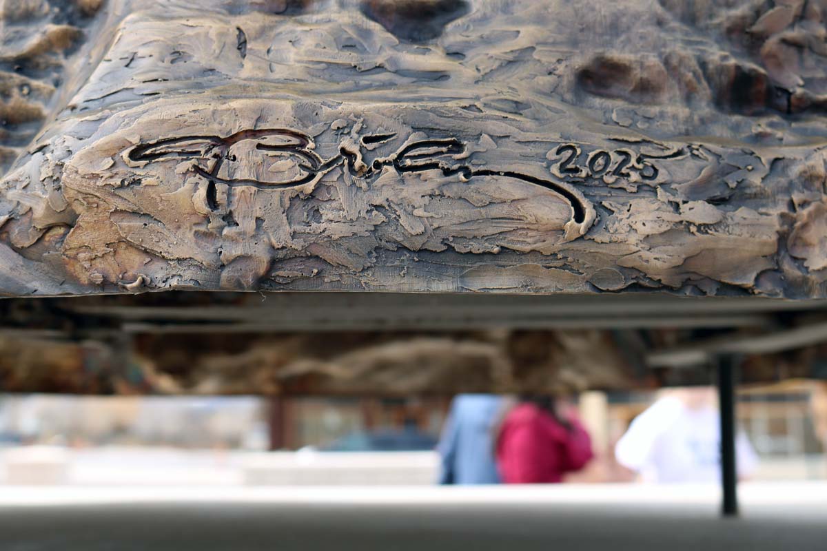 An abstract signature at the base of a bronze statue.