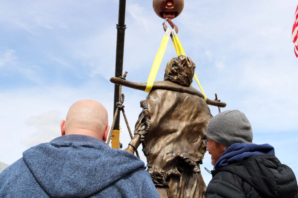 Two men looking at a bronze statue in the air.