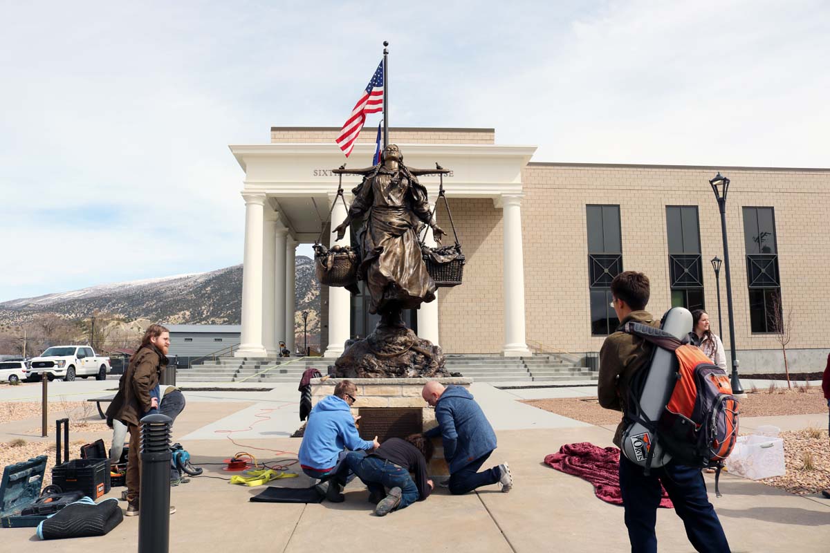 Spectators looking at the placement of a bronze statue.
