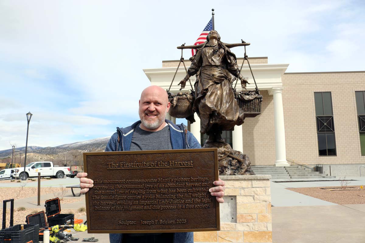 A man holding a plaque in front of a bronze statue.