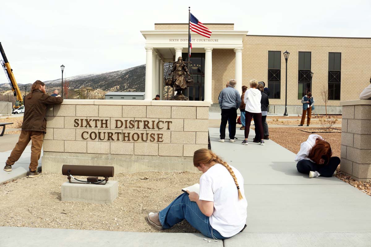 Several persons scattered in front of a courthouse writing letters.