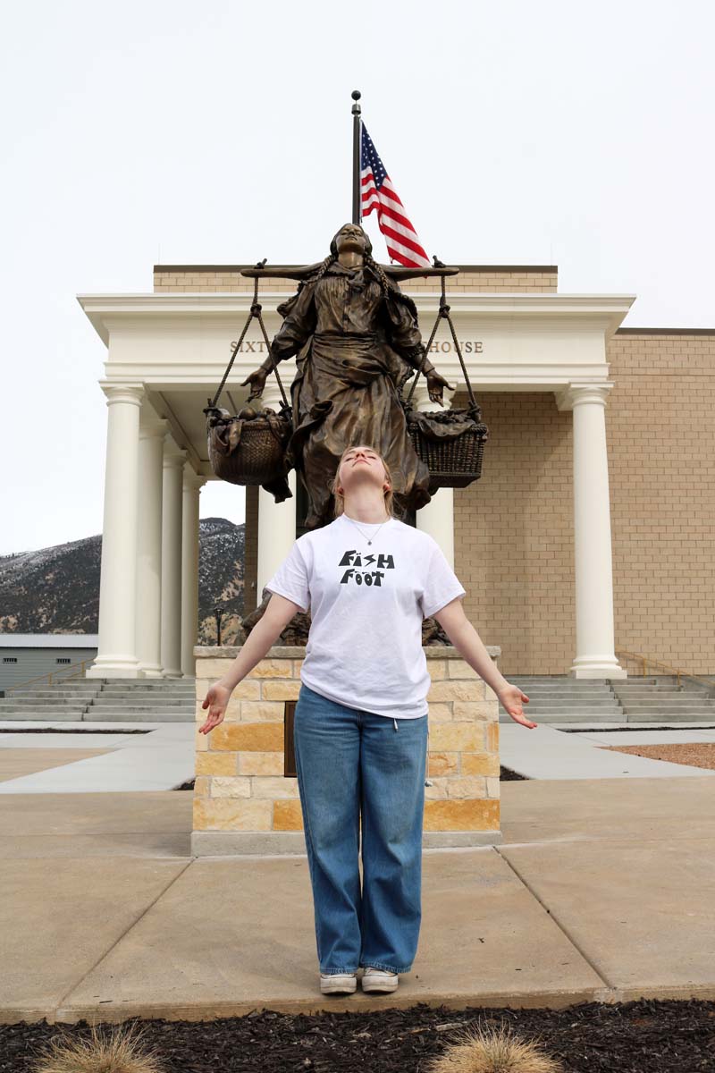 A young woman posed in front of a bronze statue,