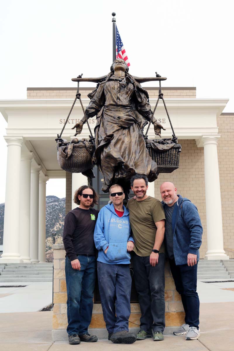 Four men in front of a bronze statue.