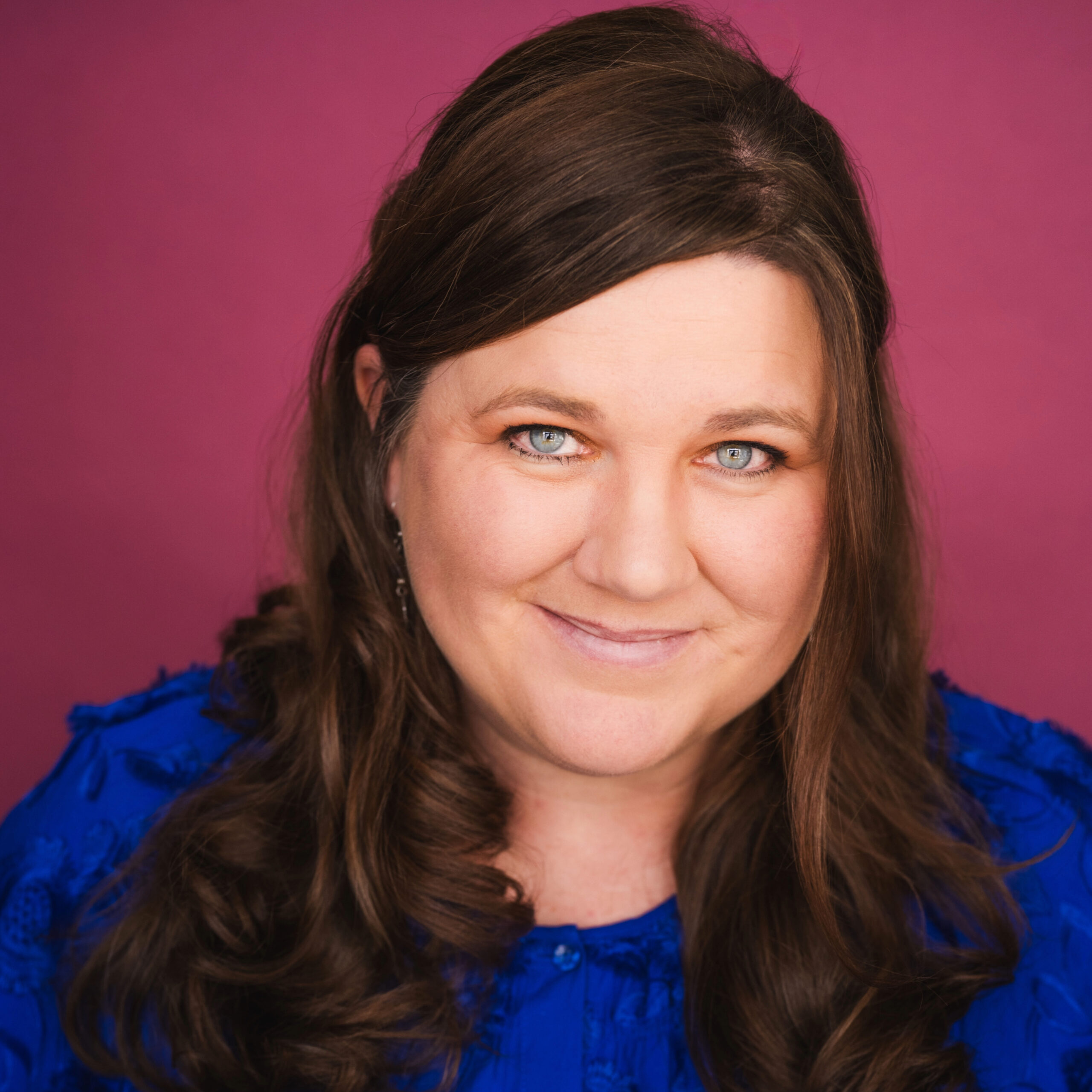 A woman with long brown hair wearing a blue shirt.