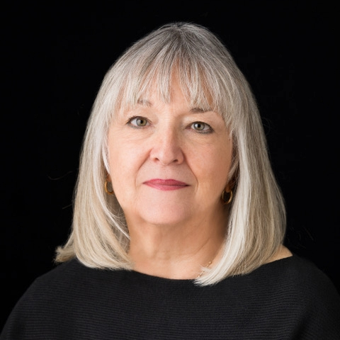 A woman with gray hair wearing a black top.