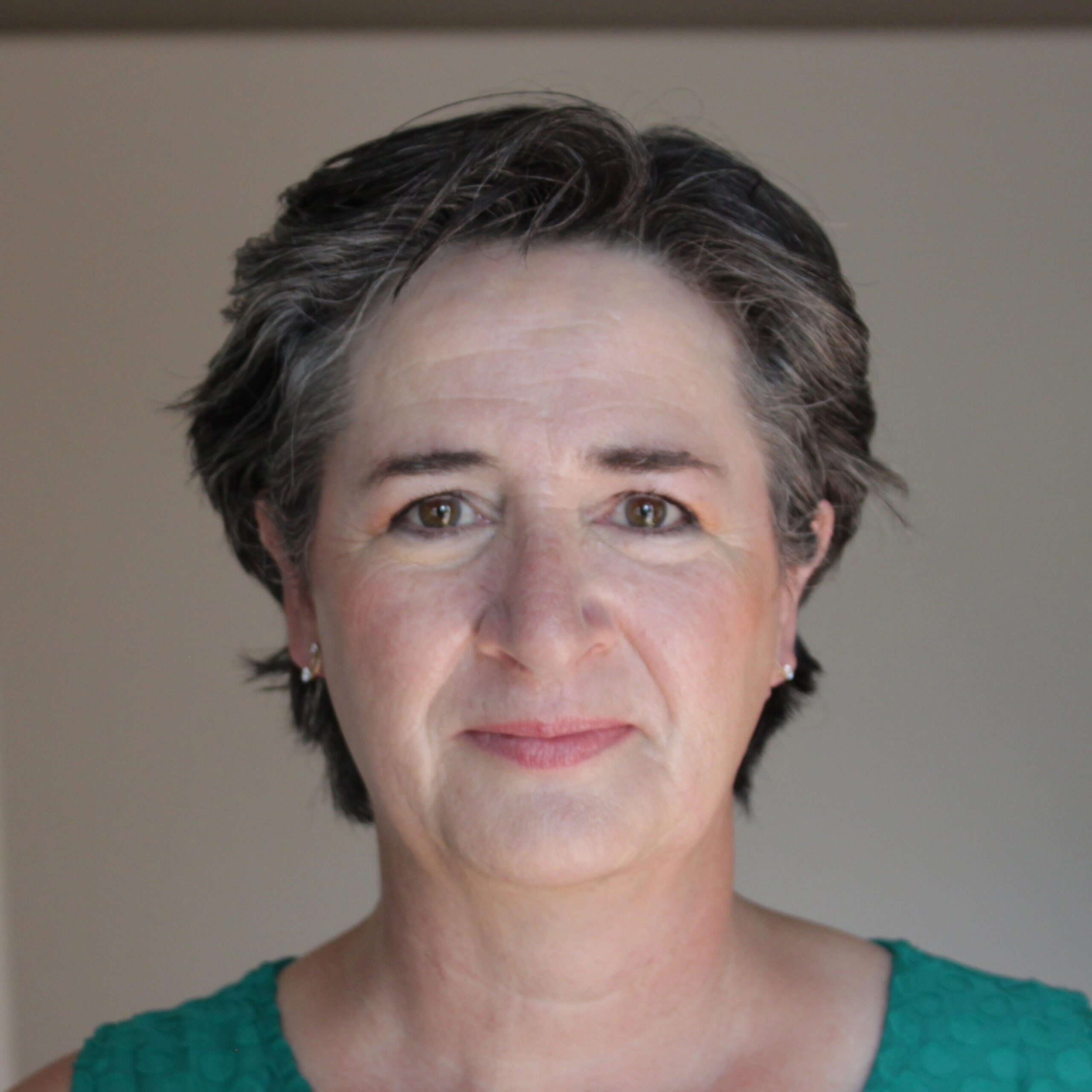 A woman with short dark hair wearing a green top.