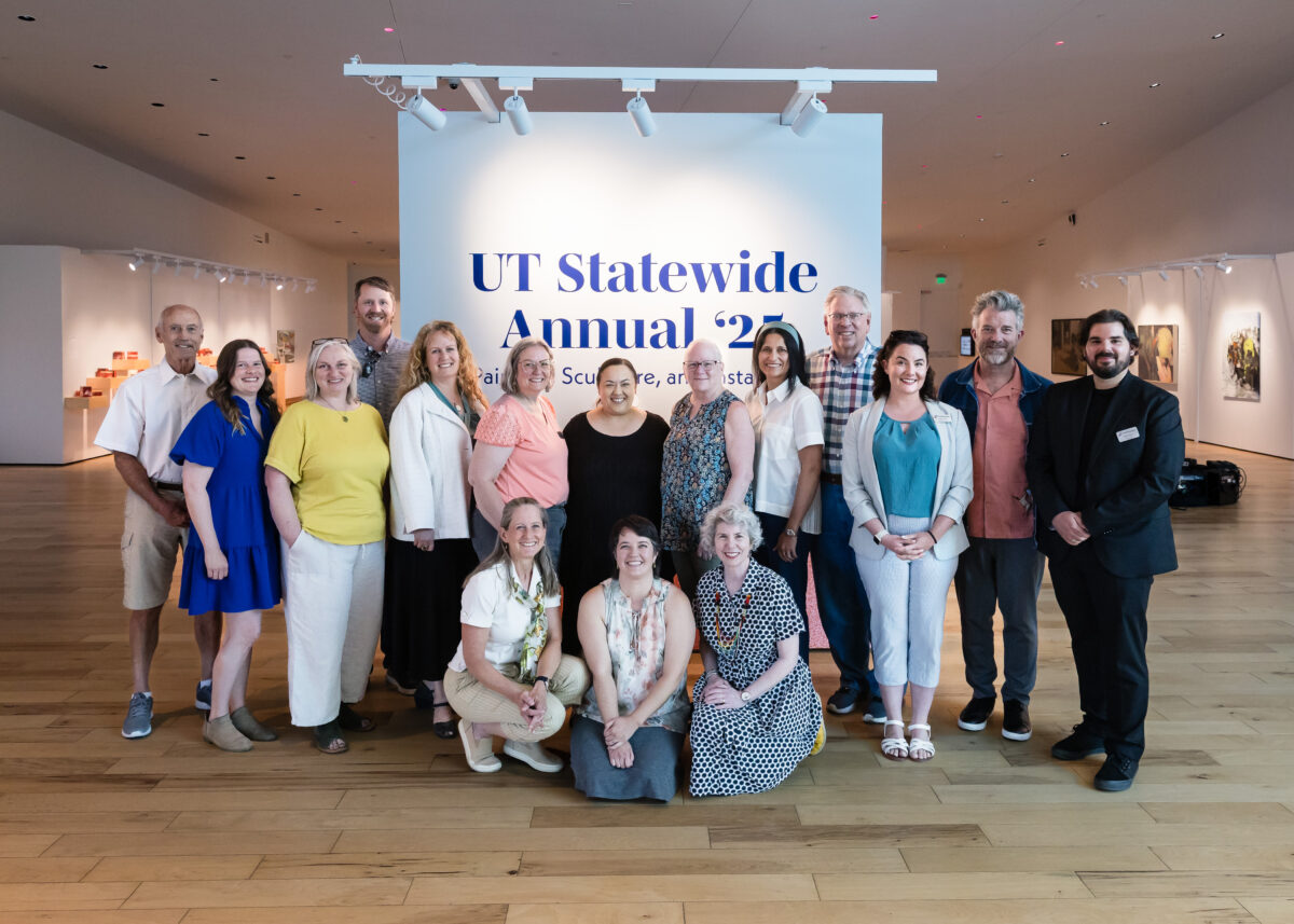 A group of people in a gallery poses in front of a sign reading "UT Statewide Annual 25."