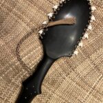 Wooden tool edged with shark teeth, resting on woven mat background.